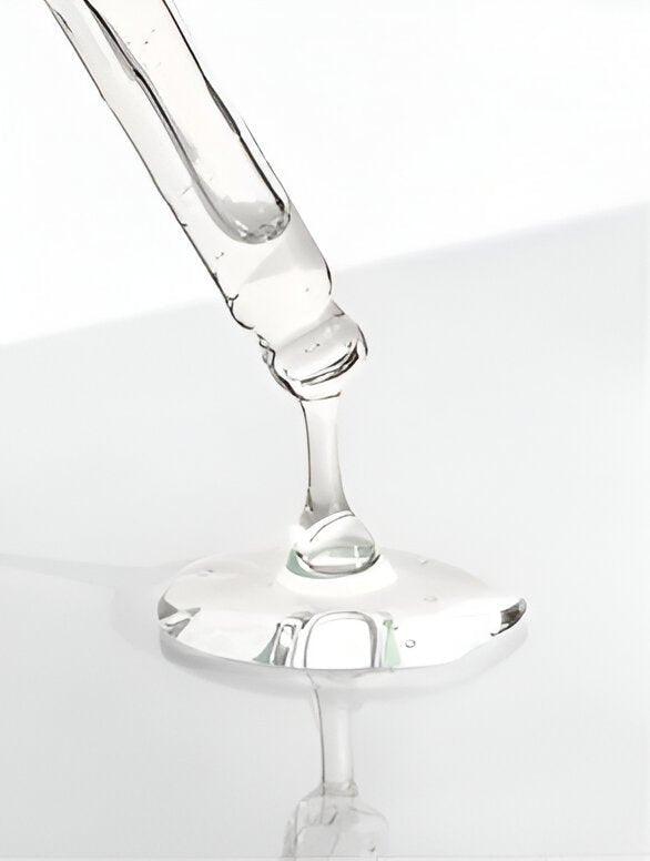 Eclat Soin Lactic acid exfoliator dripping from a pipette on a reflective surface